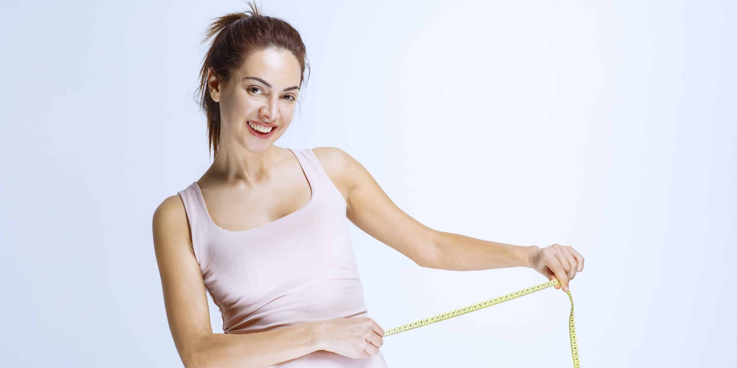 Slim girl checking the size of her waist with a tape